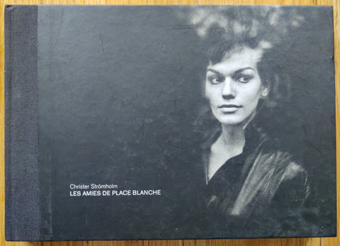 The photography book cover of Les Amies De Place Blanche by Christer Stromholm. Hardback black cover with image of a woman on the front.