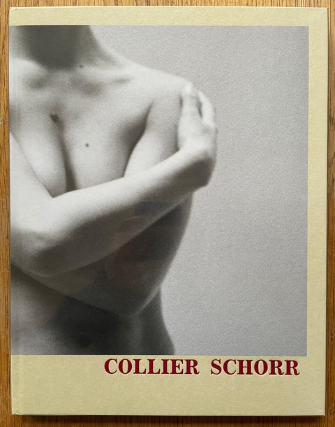 The photography book cover of 8 Women by Collier Schorr. Hardback in yellow with red author name and image of a naked person crossing their hands over their body.