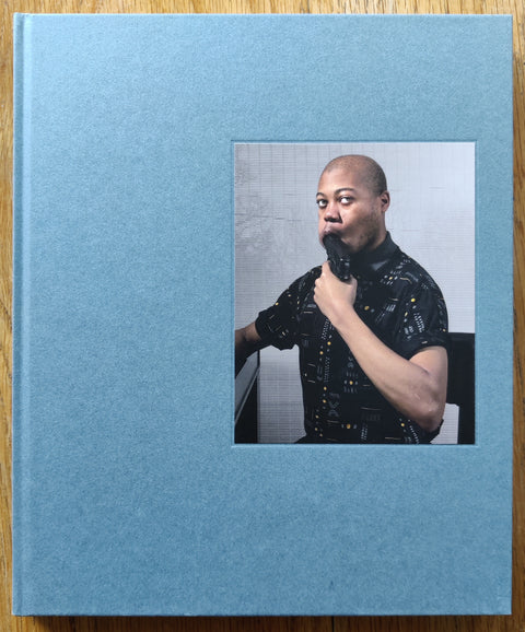 The photobook cover of Contact High by D'Angelo Lovell Williams. In hardcover blue with a person holding a gun in his mouth. Signed.