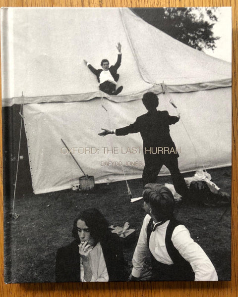 The photography book cover of Oxford: The Last Hurrah by Daffyd Jones. hardback with B&W image of students, one of them sliding off a marquee.