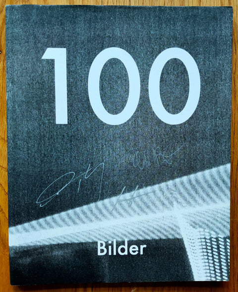 The photography book cover of 100 Bilder by Daisuke Yokota, Yoshi Kametani and Hiroshi Takizawa. Paperback in black and white with large 100 in white. Signed.