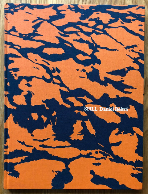 The photography book cover of Spill by Daniel Beltra. Hardback in orange and black.