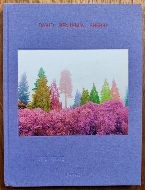 The photography book cover of It's Time by David Benjamin Sherry. Hardback in purple with image of pink and green trees.