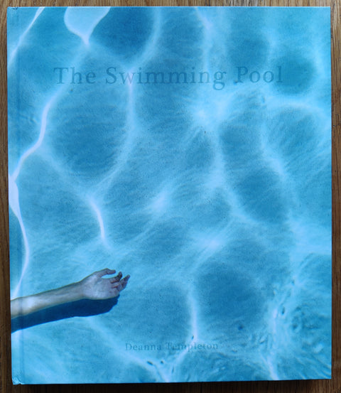 The photography book cover of The Swimming Pool by Deanna Templeton. In hardcover blue with a naked woman