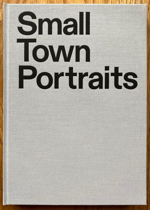 The photography book cover of Small Town Portraits by Dennis Dinneen. Hardback in light grey with large title.
