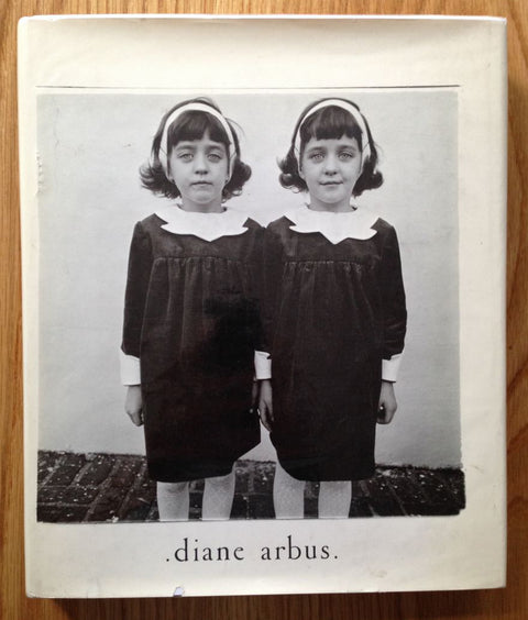The photography book cover of Diane Arbus. In dust jacketed hardcover white with her famous photo of the twin girls.