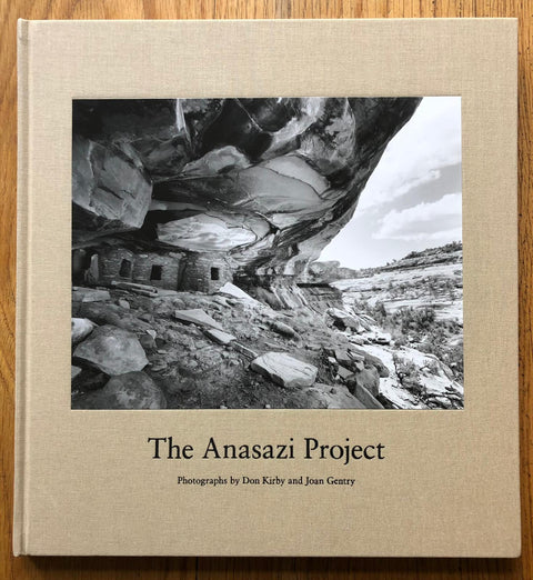 The photography book cover of The Anasazi Project by Don Kirby and Joan Gentry. Hardback in beige with image of a cliff edge/cave.