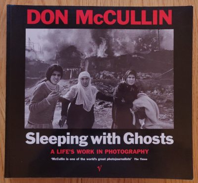 The photography book cover of Sleeping with Ghosts by Don McCullin. Hardback in black white and red.
