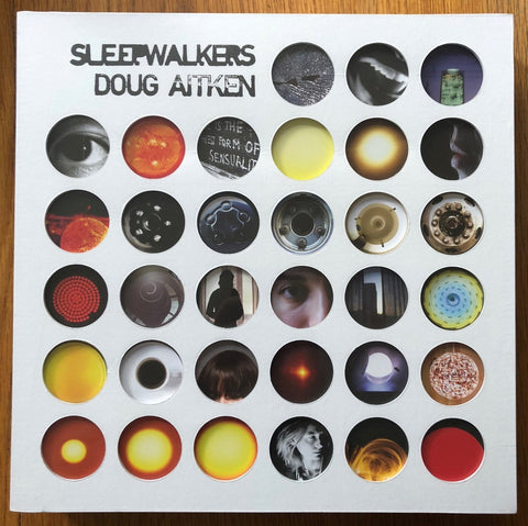 The photography book cover of Sleepwalkers by Doug Aitken. Box set containing a book, a cd, a DVD, a picture disc vinyl LP two flip books, and a poster.