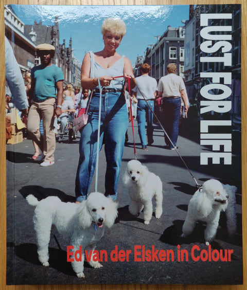 The photography book cover of Lust for Life by Ed van der Elsken. Hardback with photo of a lady walking three white dogs.