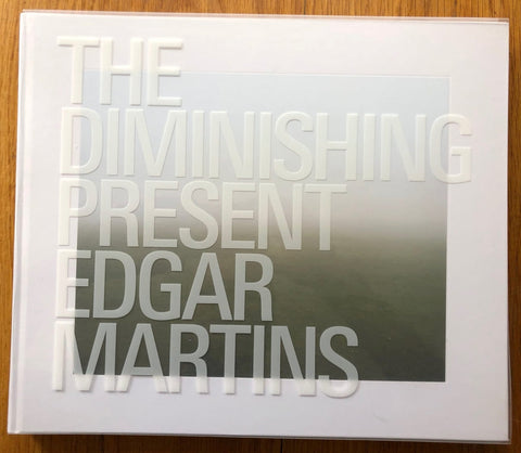 The photography book cover of The Diminishing Present by Edgar Martins. Hardback with white border and large text.