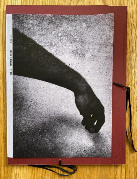 The photography book cover of Fable by Elie Monferier. Paperback with image of hand on the cover. Red card envelope with black ribbon. Signed.