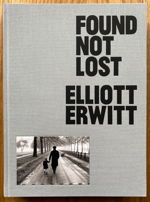 The photography book cover of Found not Lost by Elliott Erwitt. Hardback in grey with image of an adult and child walking down a path.