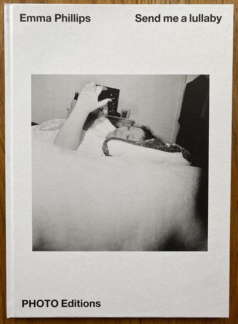 The photography book cover of Send Me a Lullaby by Emma Phillips. Hardback with image of a woman lying down on her phone.