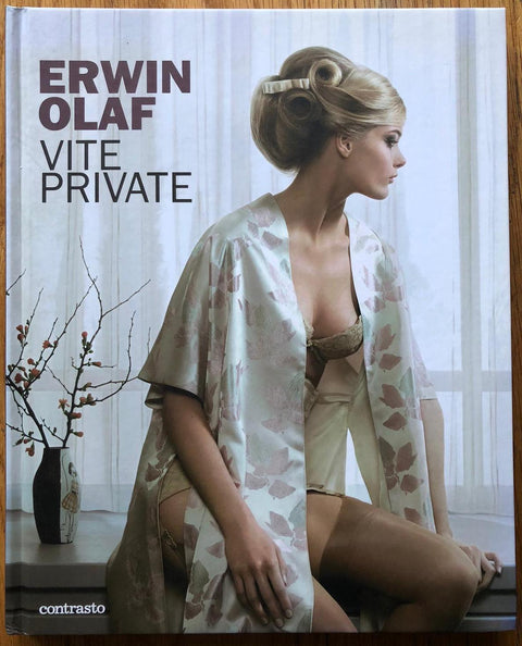 The photography book cover of Vite Private by Erwin Olaf. Hardback with a woman in a silk robe sat on the edge of a counter.