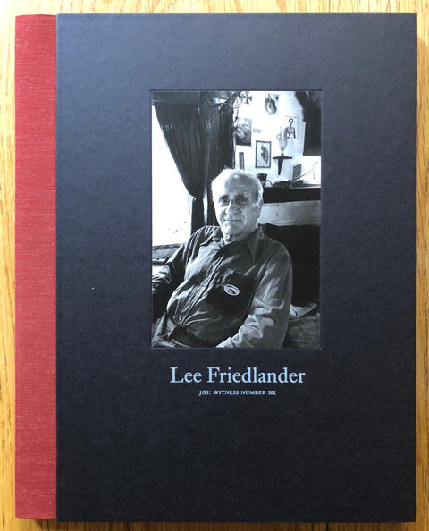 The photography book cover of JGS: Witness Number Six by Lee Friedlander. Hardback in black with b&w image of an elder man looking into the camera and a red spine.