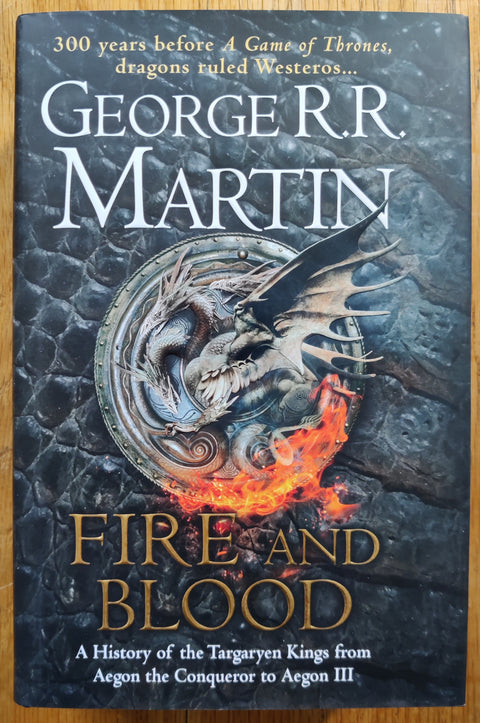 The book cover of Fire and Blood: 300 Years Before A Game of Thrones by George R. R. Martin. In dust jacketed hardcover black. Signed by George R R Martin to title page.