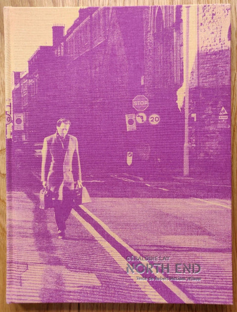 The photography book cover of North End by Geraldine Lay. Hardback image of man walking down the street with pink tinge.
