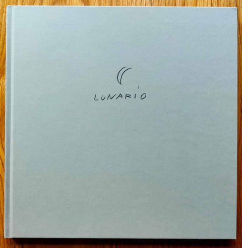 The photography book cover of Lunario, 1968-1999 by Guido Guidi. Hardback in off-white with a moon above the title. Signed.