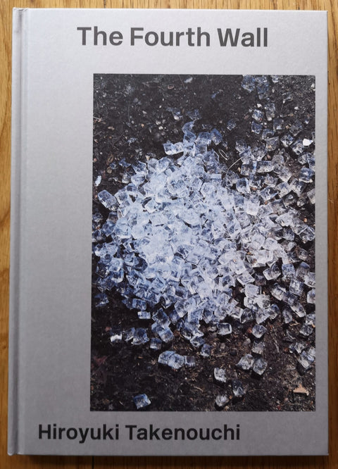 The photobook cover of The Fourth Wall by Hiroyuki Takenouchi. Hardback in grey with photo of smashed ice/glass on the ground.