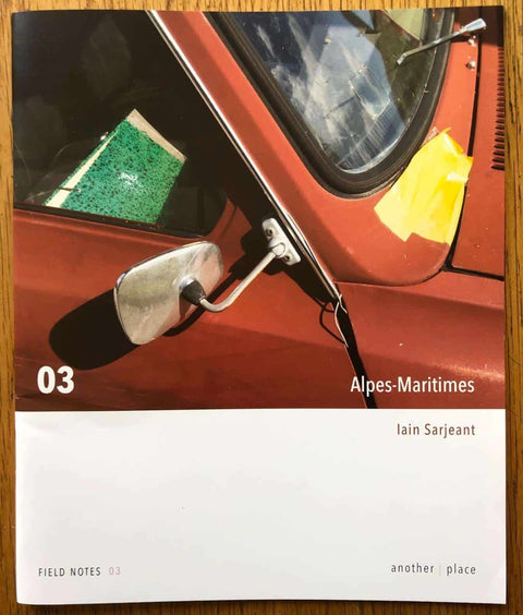 The photobook cover of Field Notes 03: Alpes-Maritimes by Iain Sarjeant. Paperback with close up image of a red car side mirror. Signed.