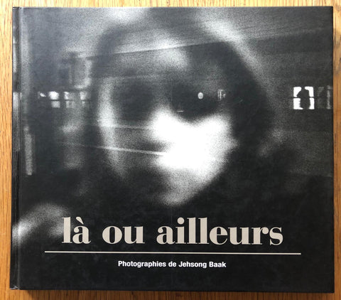 The photography book cover of La ou Ailleurs by Jehsong Baak. Hardback black and white blurry image of a woman.