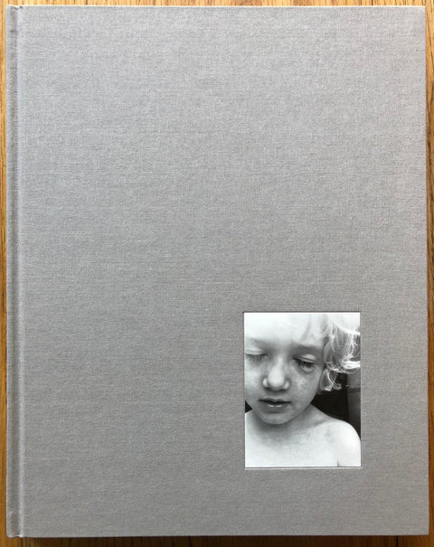 The photography book cover of The Locusts by Jesse Lenz. Hardback in light grey with image of a young boy in the bottom corner.