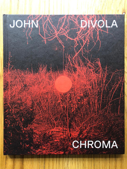 The photography book cover of Chroma by John Divola. Hardback in black with red lighting image.