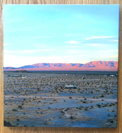 The photography book cover of Isolated Houses by John Divola. Hardback image of the desert and mountains.