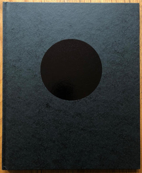 The photography book cover of Terminus by John Divola. Hardback in black with shiny black centred circle. Signed.
