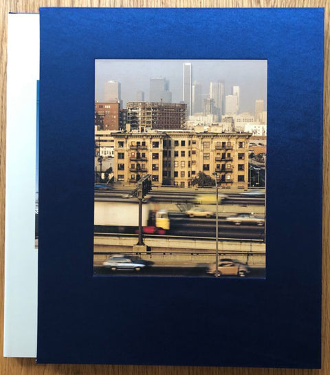 The photography book cover of Manifest Destiny. Hardback in a blue slipcase with photo of a city.