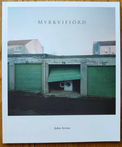 The photography book cover of Myrkvifiord by John Irvine. Paperback photograph of an open green-doored storage unit with a washing machine inside.