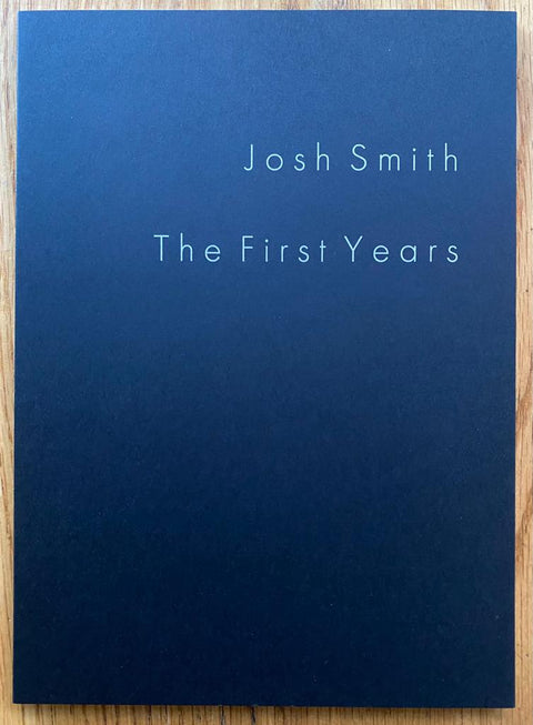 The photography book cover of The First Years by Josh Smith. Paperback in navy blue. Signed.