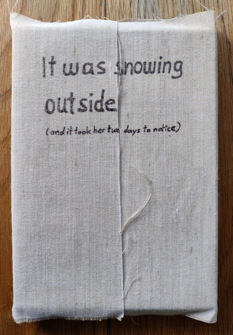 The photography book cover of It was snowing outside (and it took her two days to notice) by Jule Wild. In softcover wraparound linen fabric.