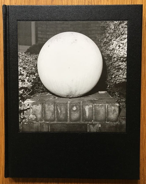 The photography book cover of A Glass Darkly by Kevin Lear. Hardback black and white cover, white ball sculpture.