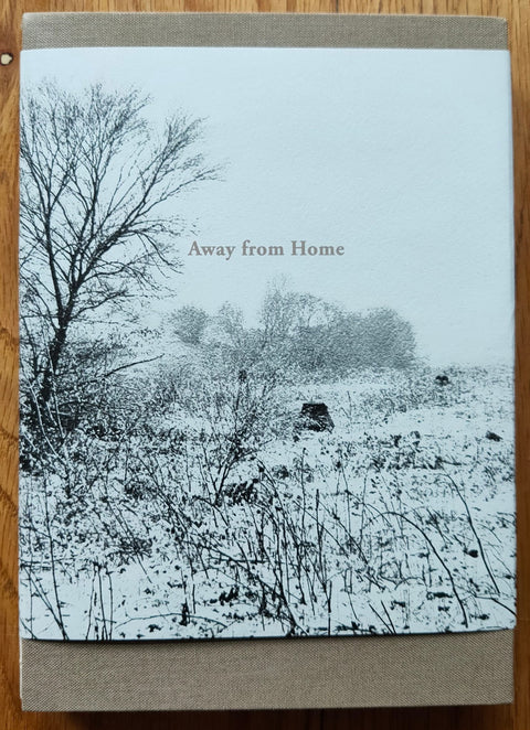 The photobook cover of Away from Home by Kursat Bayhan. Hardback with image of snowy field on the cover. signed.
