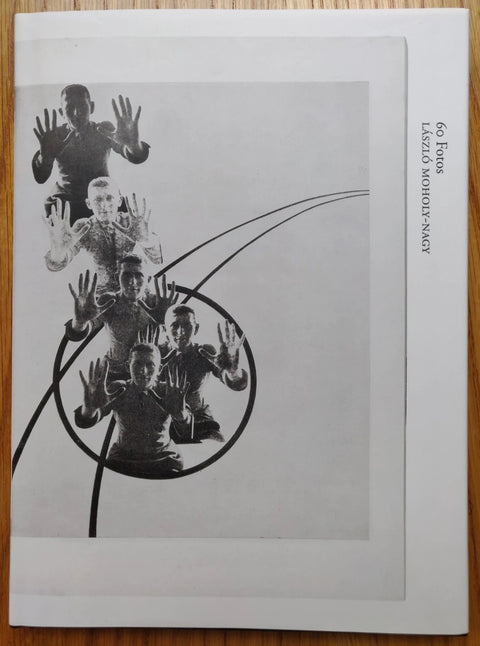 The photography book cover of 60 FOTOS by Laszlo Moholy-Nagy. Hardback in B&W with image of people holding their hands up.