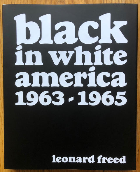The photography book cover of Black in White America by Leonard Freed. Hardback in black with large white title.