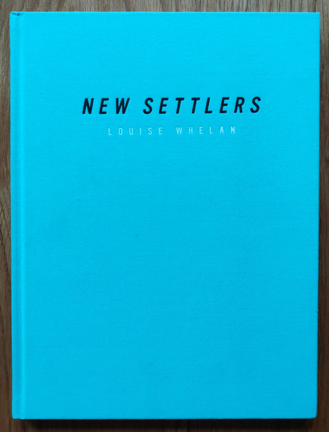The photography book cover of New Settlers by Louise Whelan. Hardback in bright blue.