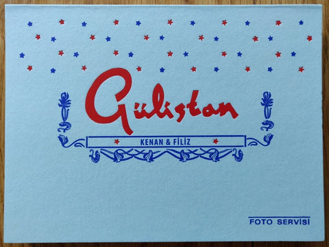 The photography book cover of GÜLISTAN by Lukas Birk and Natasha Christia. Hardback in white, with blue and red stars.