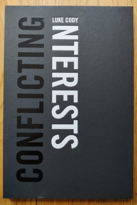 The photography book cover of Conflicting Interests by Luke Cody. Hardback in black with shiny black and white title.
