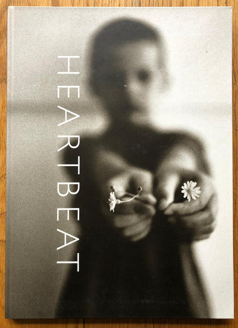 The photography book cover of Heartbeat by Machiel Botman. Hardback with image of a boy holding out two daisies. Signed.