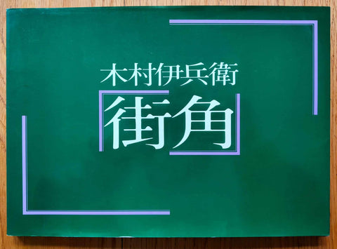 The photography book cover of Machikado (Street Corners) by Ihei Kimura. Paperback in green with purple corner lines.