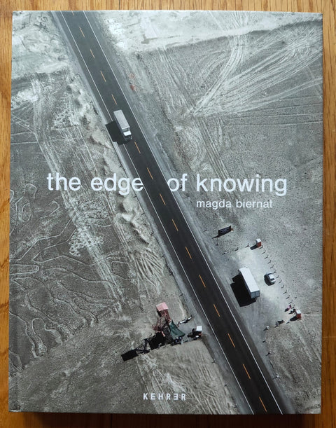 The photobook cover of The Edge of Knowing by Magda Biernat and Ian Webster. Hardback with birdseye view of a truck going along an open road. Signed.