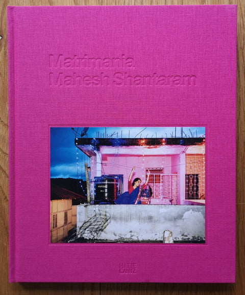 The photography book cover of Matrimania by Mahesh Shantaram. Hardback in bright pink with image of a woman dancing on a balcony. Signed.