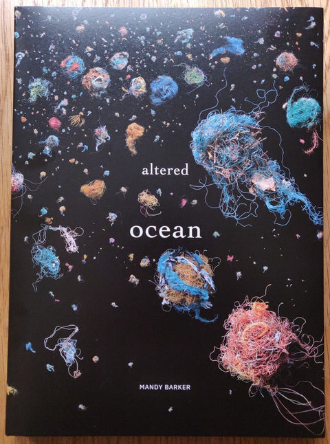 The photography book cover of Altered Ocean by Mandy Barker. Hardback in black with colourful string balls on the cover.