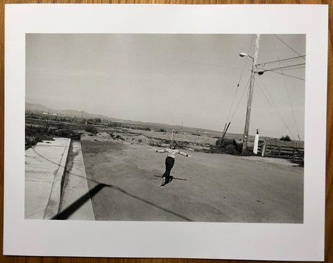 The print for Angel City West 3 by Mark Steinmetz. B&W print of a child running holding their arms out. Gold hardback book, signed.