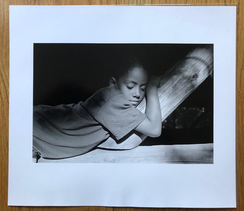 The photography book cover of Summer Camp - Special edition option A by Mark Steinmetz. Print of a little boy lying on a wooden frame. Hardback photobook in dark green. Signed.