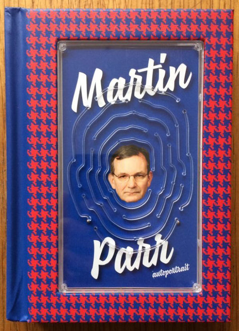 The photography book cover of Autoportrait by Martin Parr. Hardback with a blue and red cover and face in the middle.