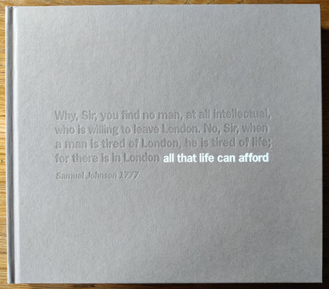 The photography book cover of the second edition of All That Life Can Afford by Matt Stuart. In hardcover grey.